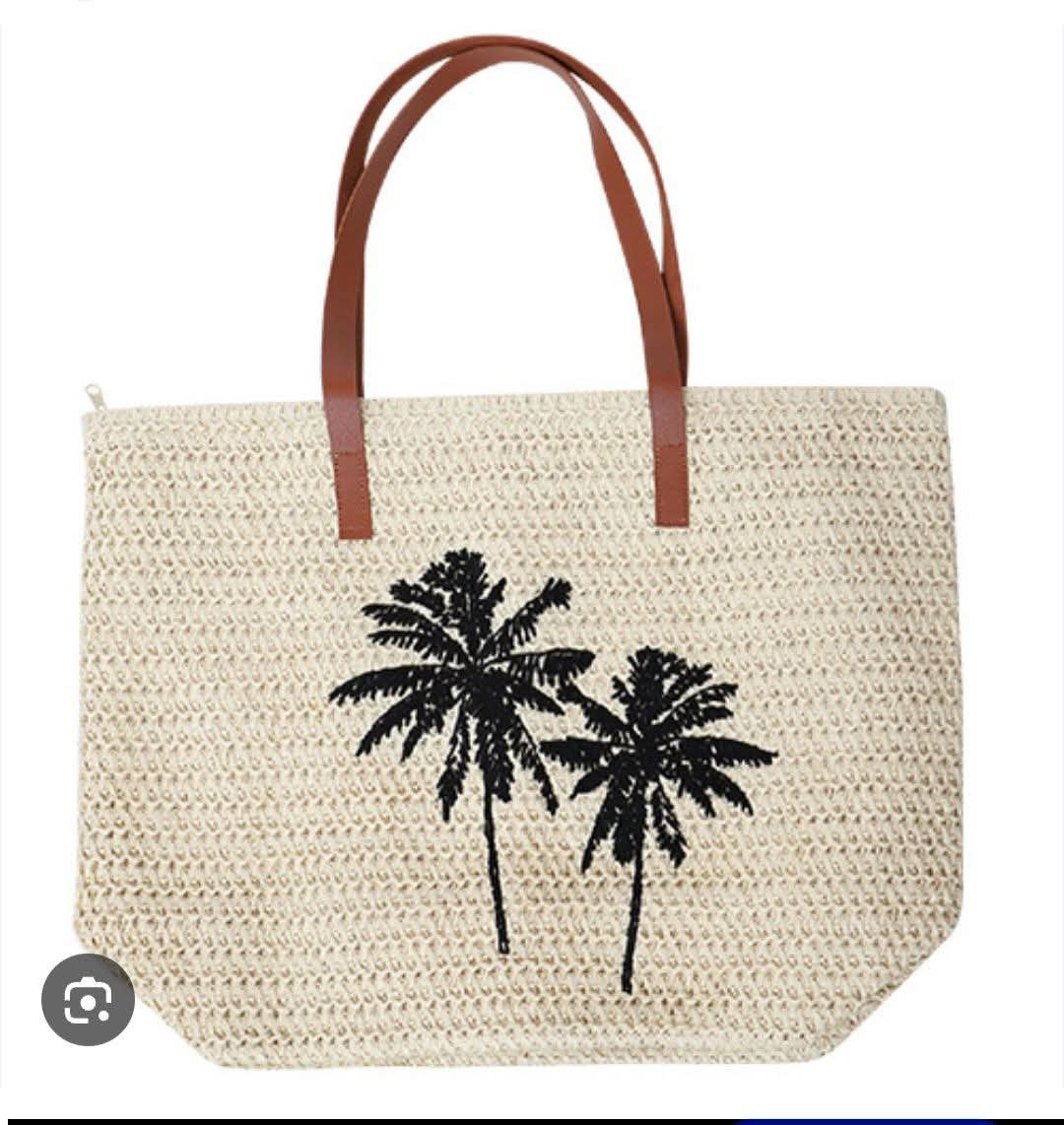 Sac de plage en paille est orné de palmiers brodés noirs et comporte des anses en cuir brun.