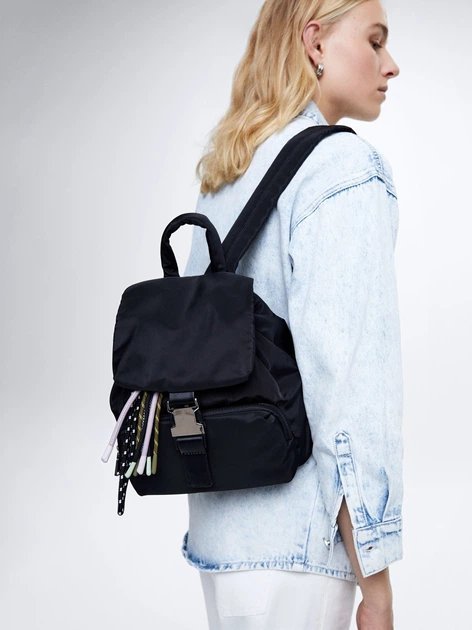 Un sac à dos noir en nylon, caractérisé par sa fermeture à boucle distinctive sur le rabat avant
