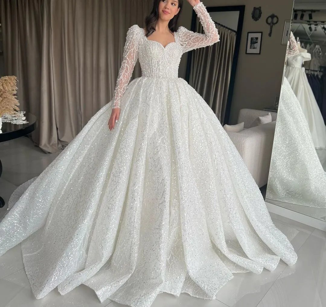 Robe de mariée blanche de style princesse se distingue par ses manches longues et ses détails scintillants lazmeha chway retouche 