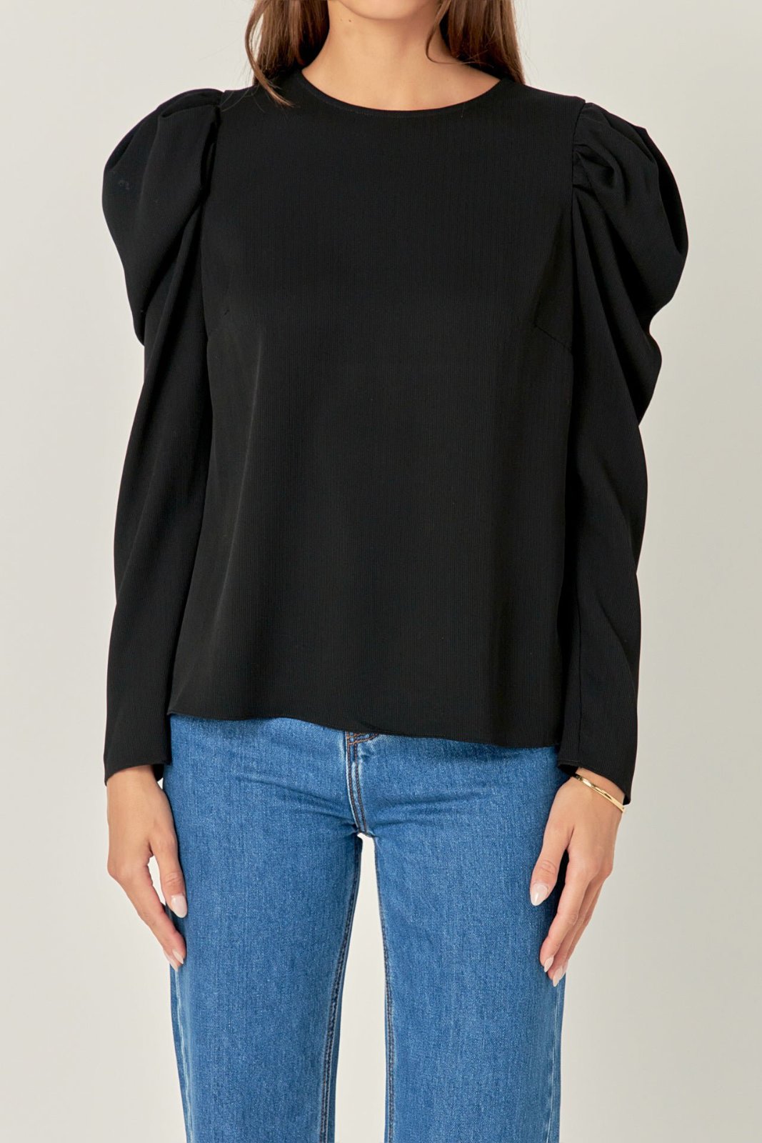 Blouse H&M noire se distingue par ses manches bouffantes volumineuses et son col rond