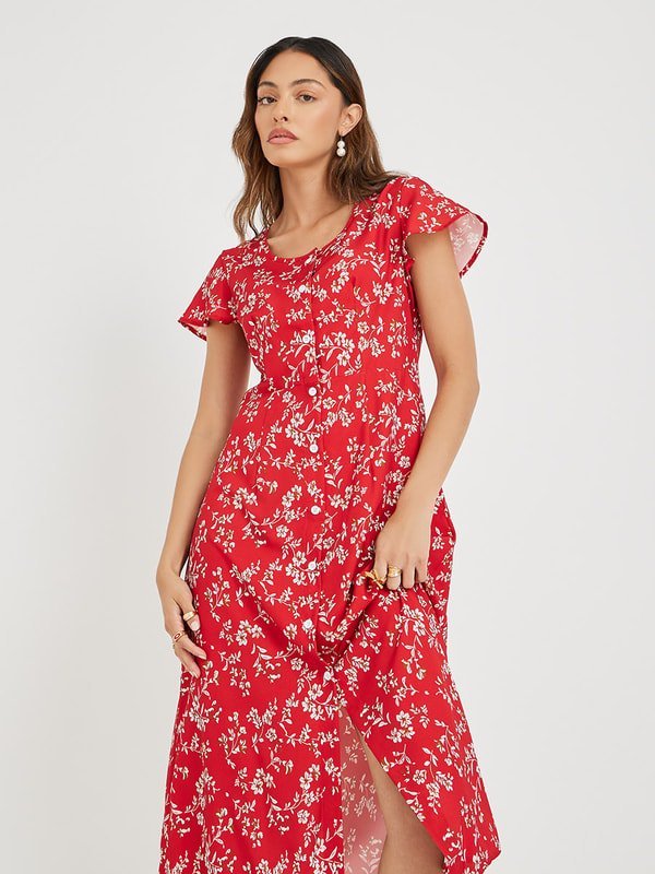 Une robe mi-longue rouge à imprimé floral blanc et manches courtes, agrémentée d'une patte de boutonnage sur le devant.    