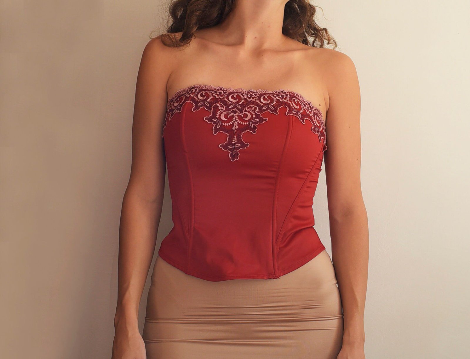 Bustier rouge vif présente une broderie complexe en dentelle blanche sur le décolleté.