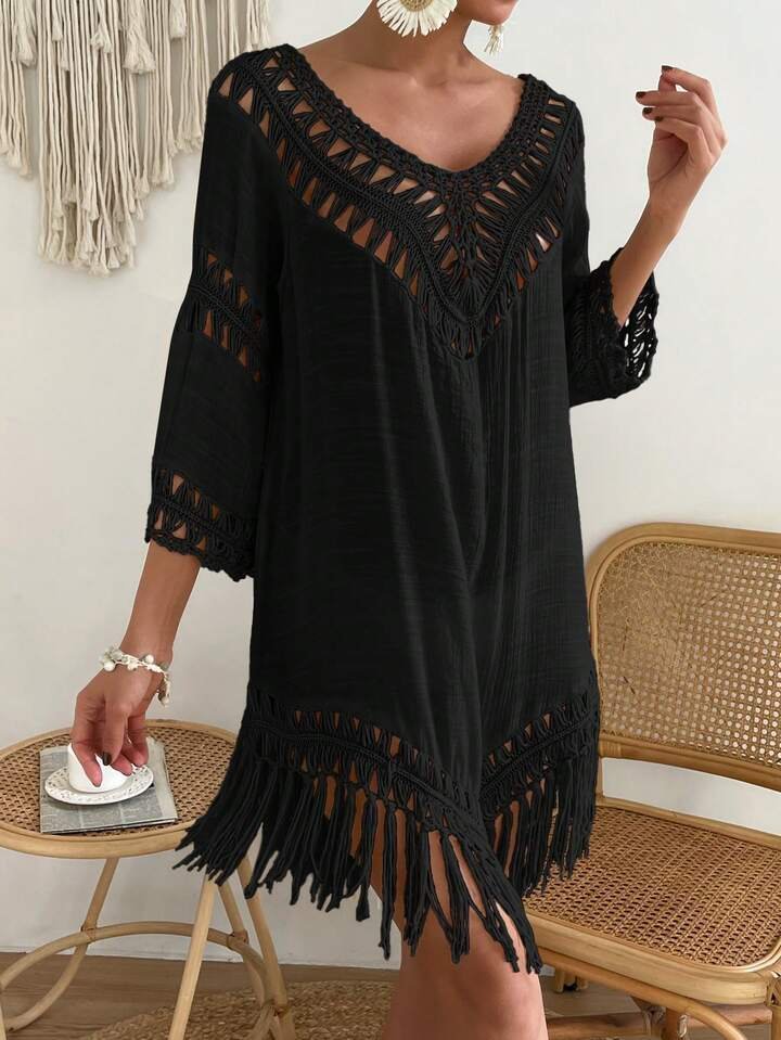  tunique de plage noire de style bohème, caractérisée par ses détails en maille crochetée ajourée au niveau du décolleté en V et des manches, ainsi que par ses longues franges fluides sur un ourlet asymétrique.