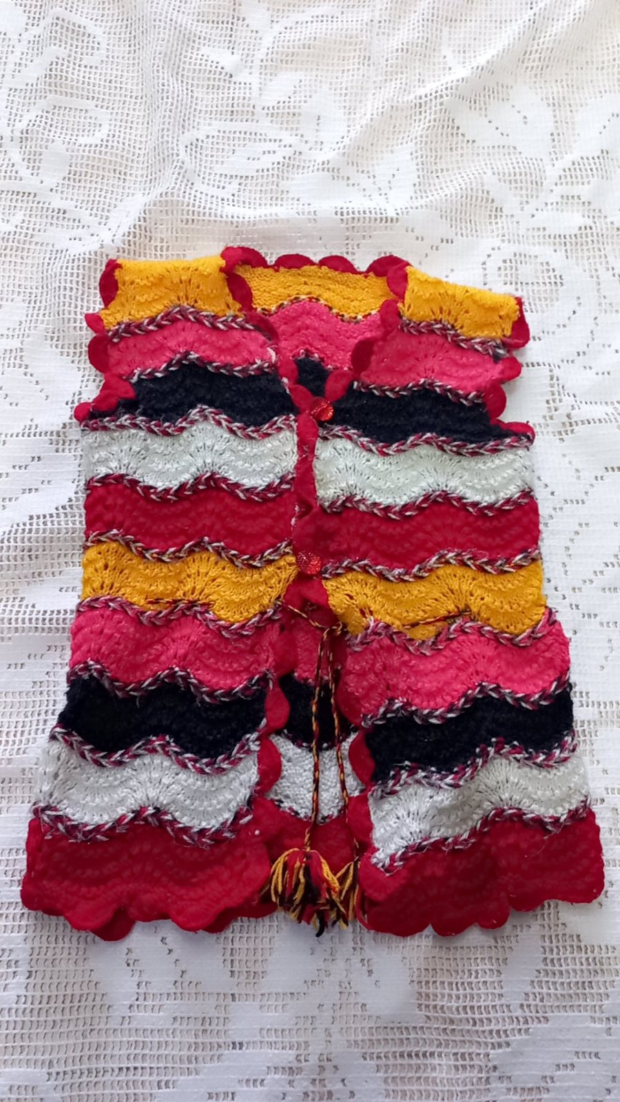 Gilet tricoté à la main avec un motif chevron et des bordures festonnées. 