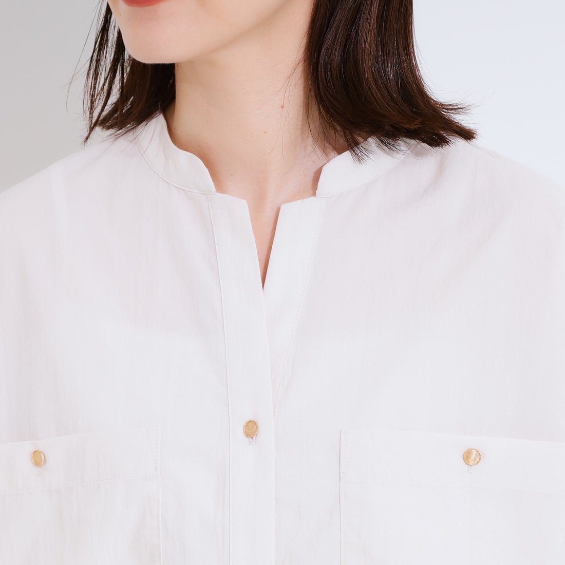 Chemise blanche satinée pour femme avec un col officier et des boutons dorés fiha tache tetgsal pressing tandaff fi ragba min tali 