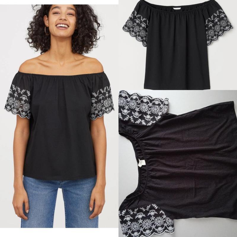 Blouse H&M noire à épaules dénudées présente des broderies blanches décoratives sur les manches courtes