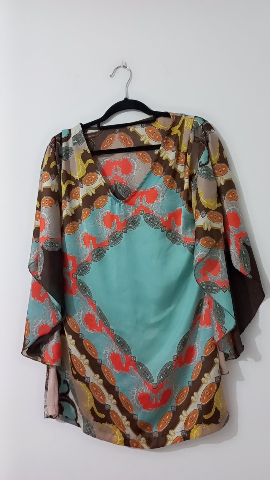 Tunique fluide à manches chauve-souris présente un motif multicolore d'inspiration baroque avec un empiècement central turquoise vif.    
