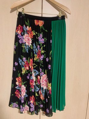 Jupe plissée Stradivarius présente un motif floral vibrant sur un fond noir avec une doublure intérieure verte
