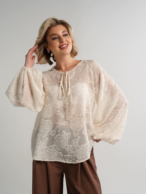 Tunique crème de style bohème est dotée d'une dentelle complexe au niveau de l'encolure et de liens réglables à pompons.