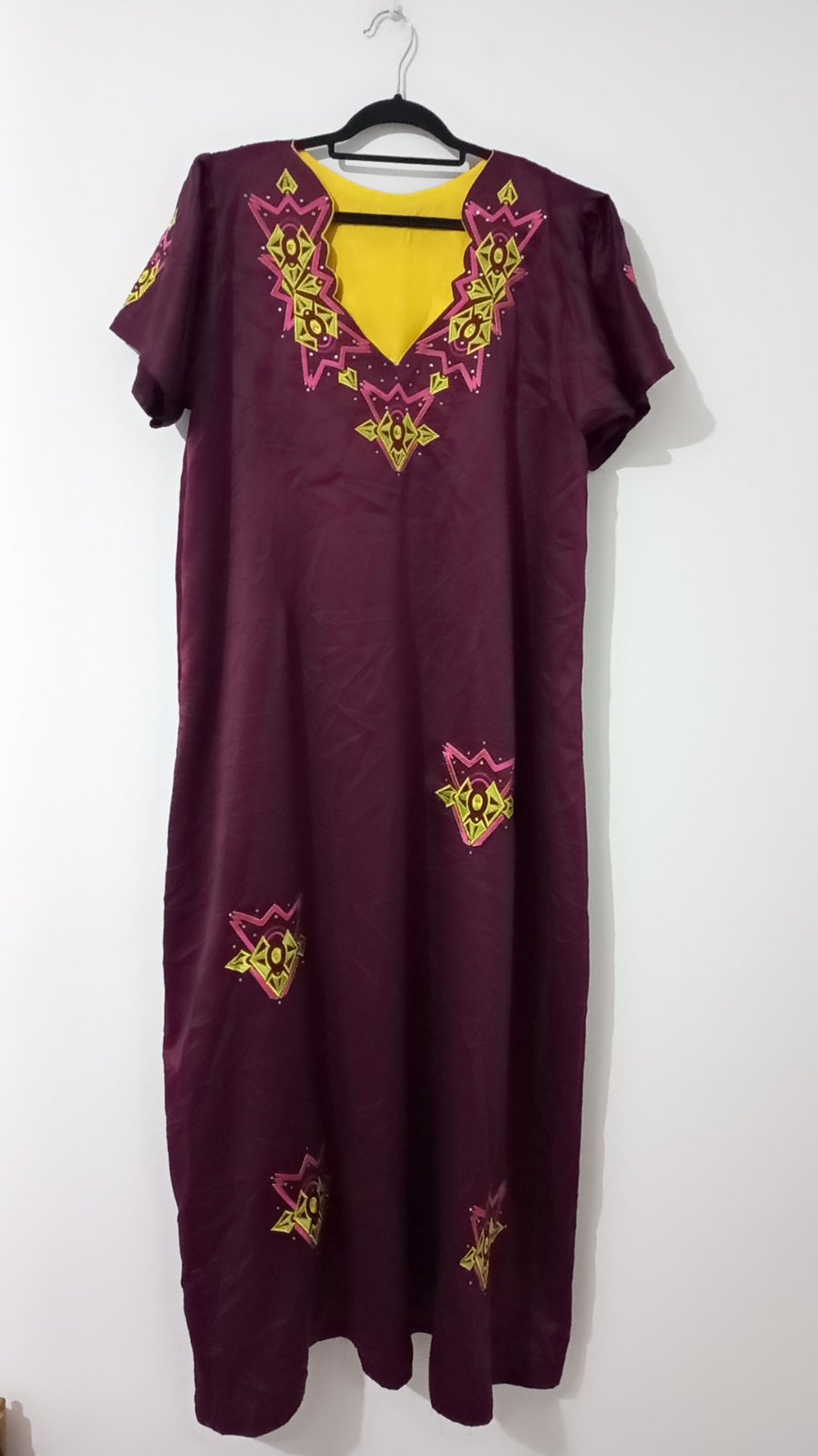 Une longue robe satin  d'intérieur ample de couleur prune, élégamment rehaussée d'un col en V à empiècement jaune et de motifs géométriques brodés multicolores