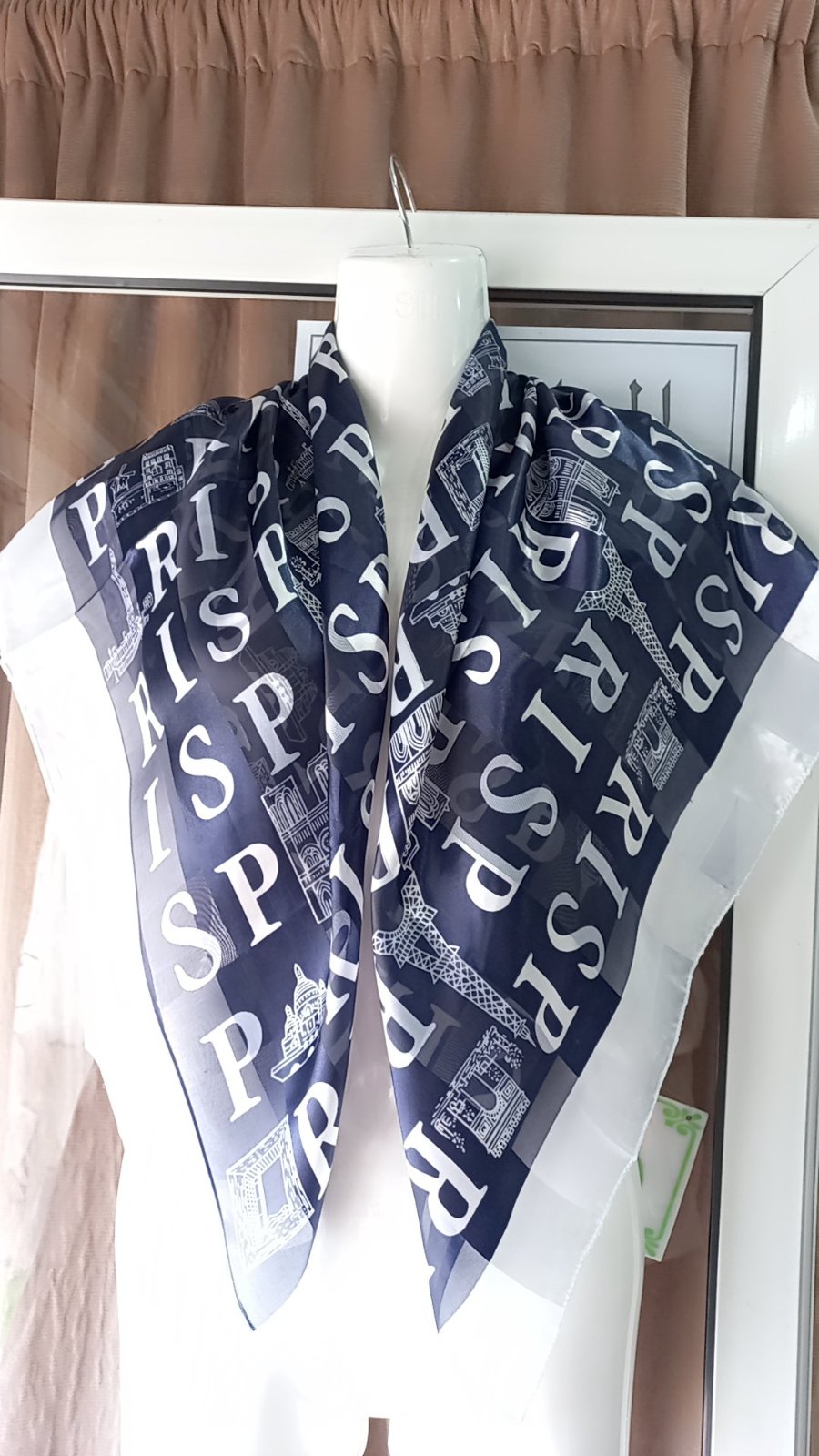 Un foulard en soie de couleur bleu marine avec des motifs imprimés représentant des monuments de Paris. 