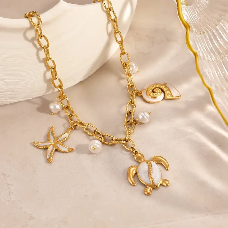 Collier à breloques maritimes non signé est fabriqué en acier inoxydable doré et se distingue par ses pendentifs en forme de tortue, d'étoile de mer et de coquillage incrustés de nacre blanche