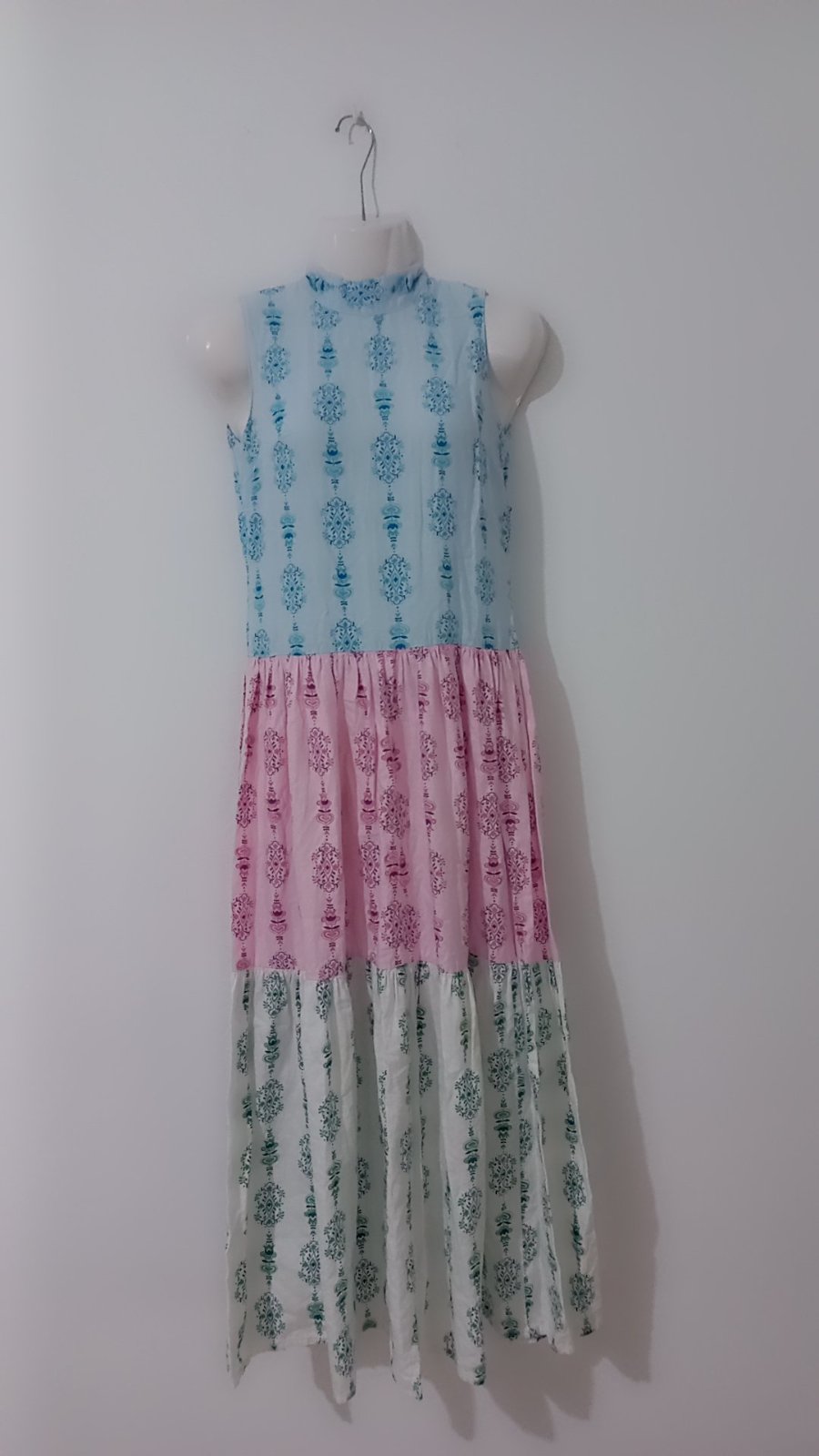Robe longue sans manches présente un design colorblock étagé en blocs de pastel bleu, rose et blanc avec des motifs traditionnels imprimés sur l'ensemble 36/38