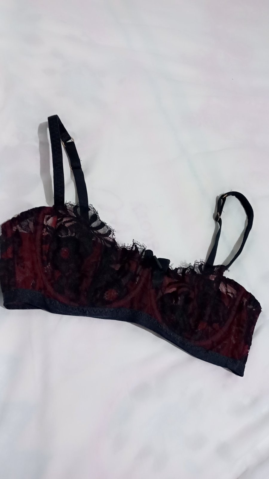  soutien-gorge balconnet Ameliah de la marque Agent Provocateur, remarquable pour sa dentelle fine noire superposée à une doublure en tulle rouge bordeaux.