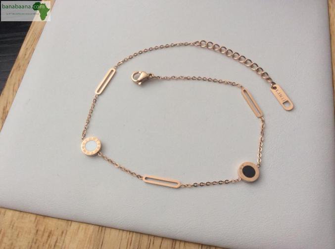 bracelet de la marque AiBang Ni en acier inoxydable de couleur or rose, dont le design s'inspire de la collection Bvlgari Bvlgari avec des éléments circulaires et un médaillon central en onyx noir. 