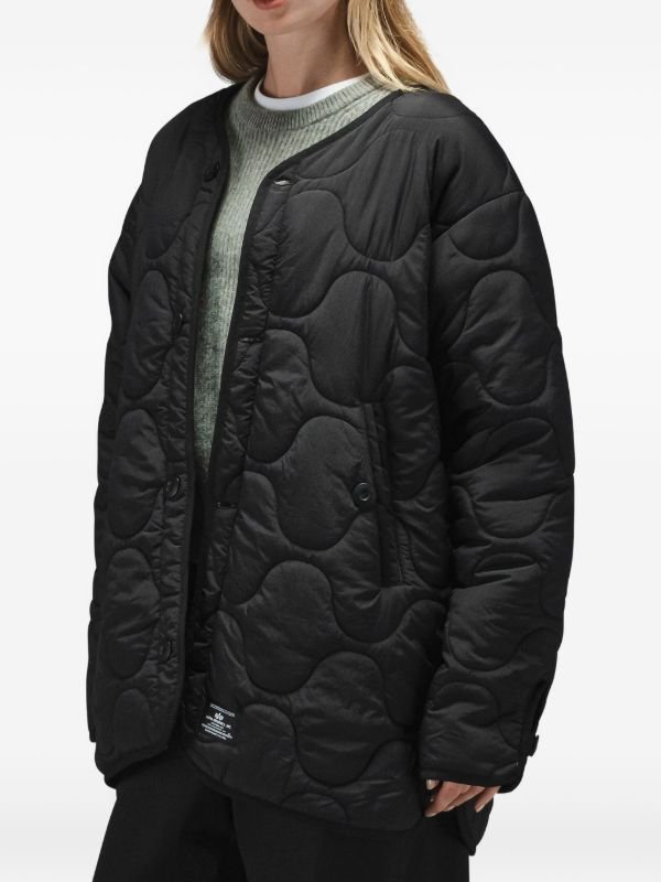 Veste matelassée noire de style "inner blouson" ou doublure, comportant des poches avant et une fermeture éclair.