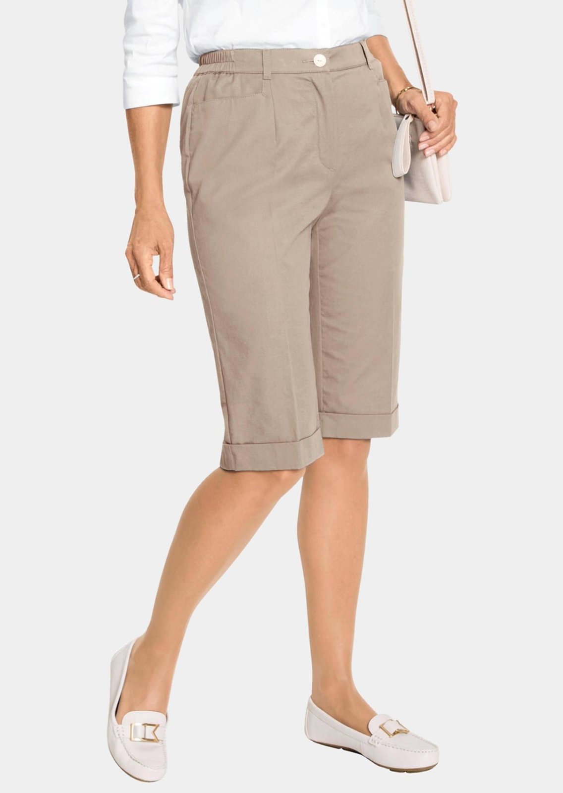 Pantacourt beige de style chino pour femme présente une coupe décontractée et des revers aux ourlets.