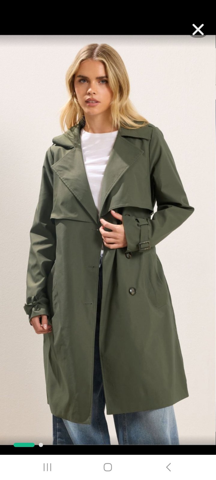 Un élégant trench-coat vert olive qui se distingue par sa doublure intérieure à rayures bleu clair et blanches