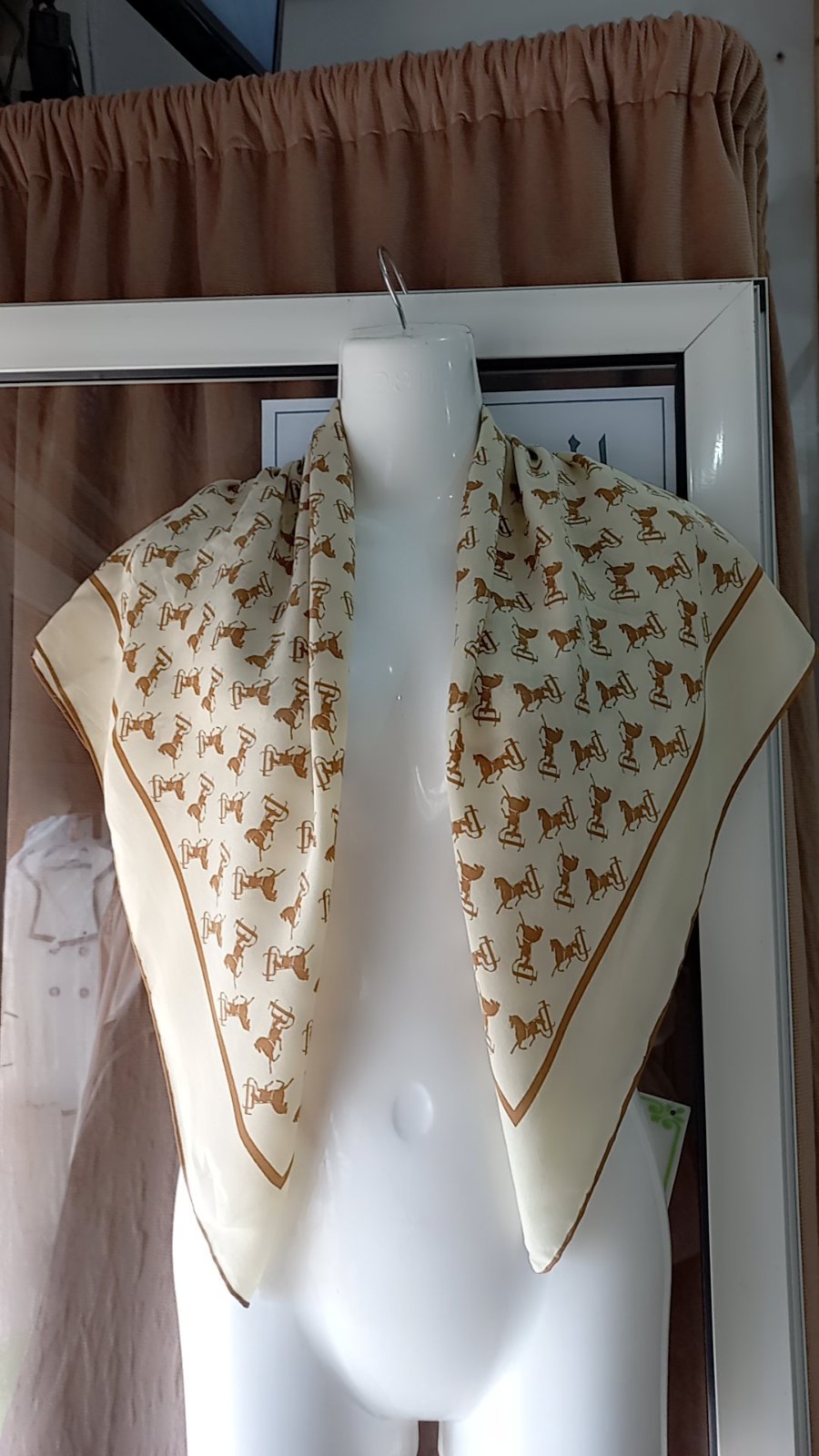 Foulard de marque Juschi présente un motif répétitif rappelant des trophées ou des objets décoratifs.