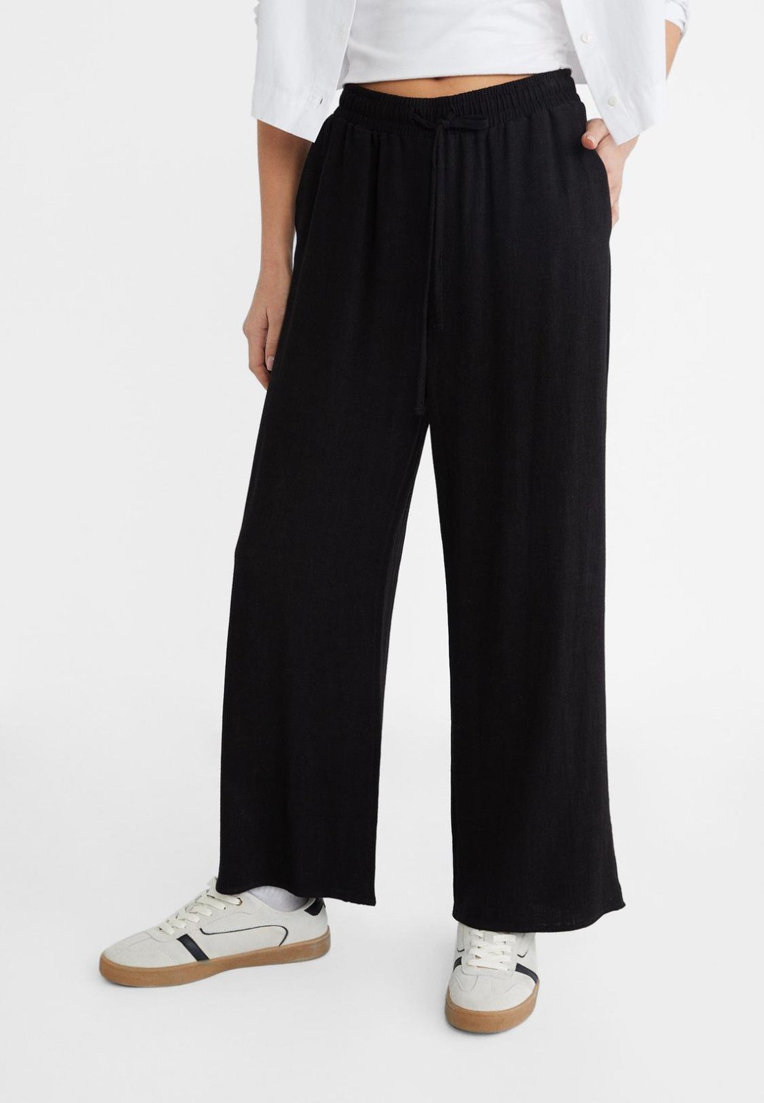 Un pantalon fluide noir doté d'une taille élastiquée froncée, offrant une coupe droite à la fois décontractée et confortable.