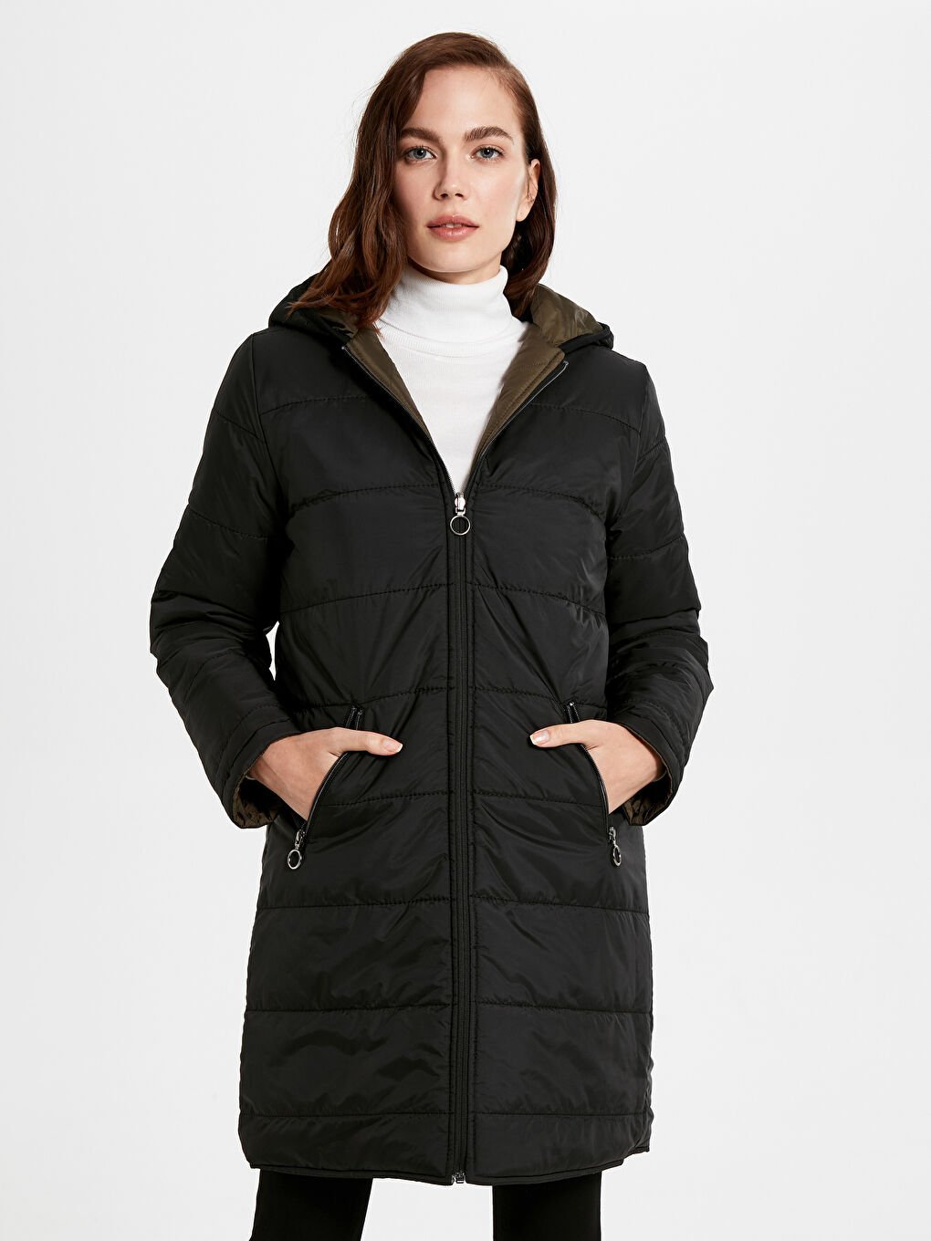 Une doudoune longue noire à capuche pour femme, identifiée comme une parka matelassée fih taftika sghira fi ydo si nn état neuf 
