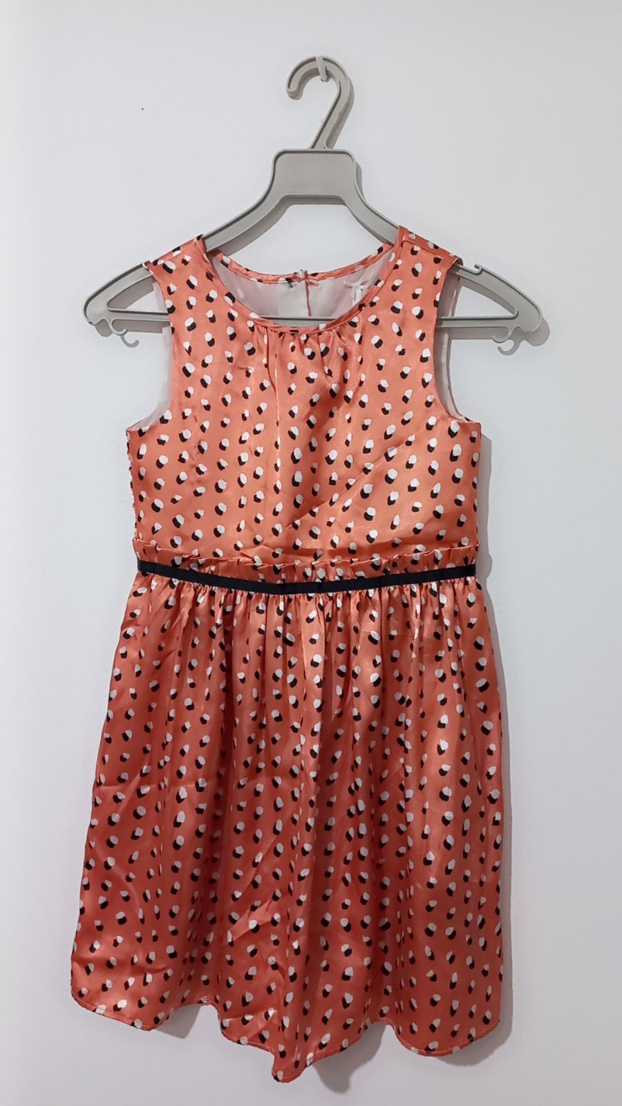 Robe corail  satiné sans manches arbore un motif géométrique abstrait composé de petites formes noires et blanches