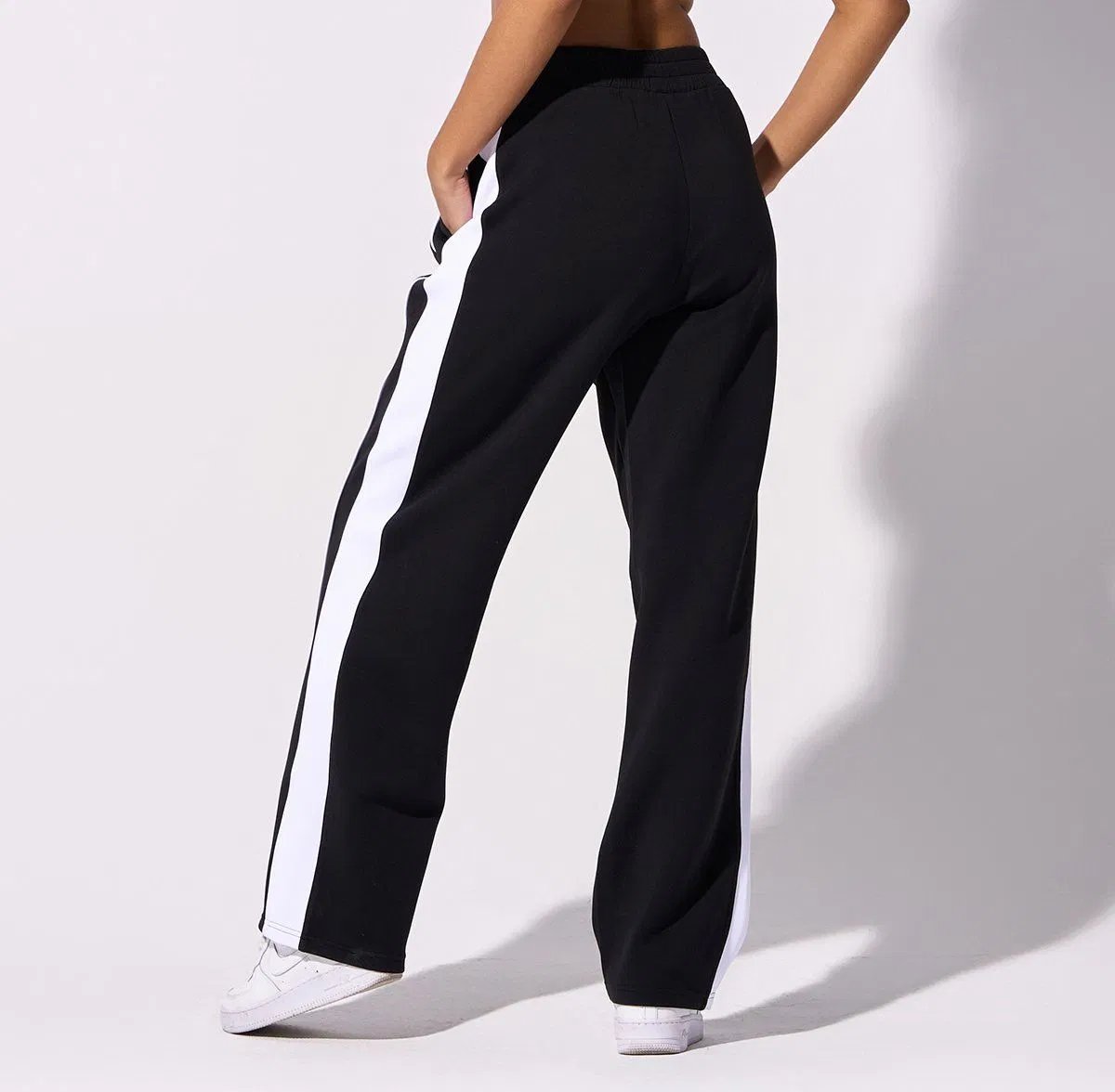 Pantalon noir fluide ressemble au modèle Side Stripe de Karl Kani avec ses bandes blanches latérales contrastées