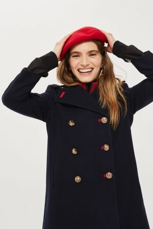  manteau caban bleu marine se distingue particulièrement par ses superbes boutons dorés et ses délicates touches de rouge contrastantes sur les boutonnières.   Nagess bouton  sans importance 