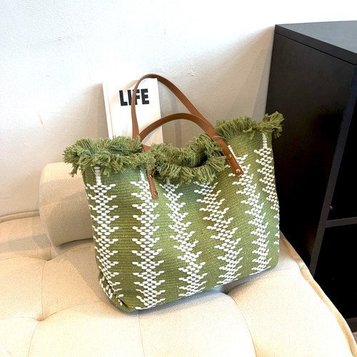 Cabas vert olive en tricot présente un motif géométrique blanc et des détails de franges sur le dessus.