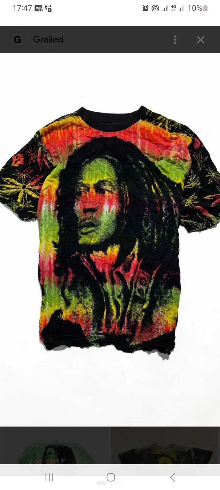  t-shirt vintage en impression intégrale (all-over print) de Bob Marley, arborant un portrait stylisé de l'artiste entouré de motifs de feuilles de cannabis aux couleurs rasta rouge, jaune et vert.