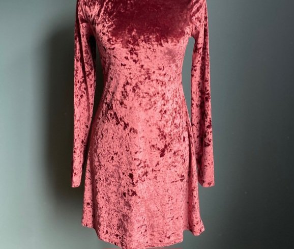Une mini-robe en velours de style patineuse, caractérisée par sa coupe ajustée au buste et évasée à la taille, souvent associée à des marques comme Topshop ou Sundance.