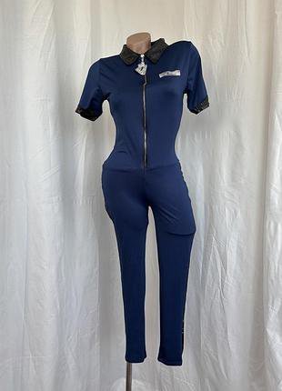 Combinaison pantalon bleu marine dotée d'une fermeture éclair frontale et de détails noirs brillants sur le col et les manches  