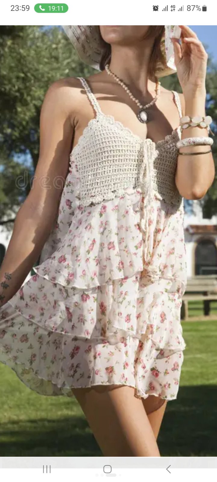 Robe est un modèle d'été avec un haut en crochet blanc et une jupe à volants à motif floral rose