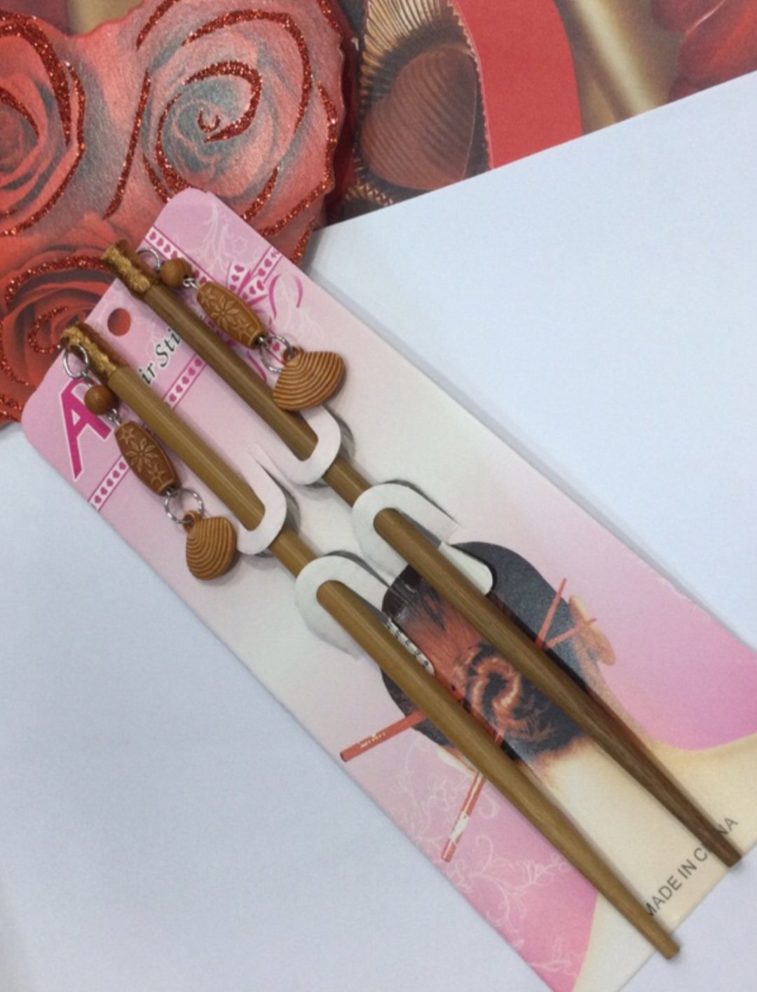 Épingles à cheveux en bois de style chinois présentent des pendentifs en forme de coquillage et sont emballées sur une carte rose.