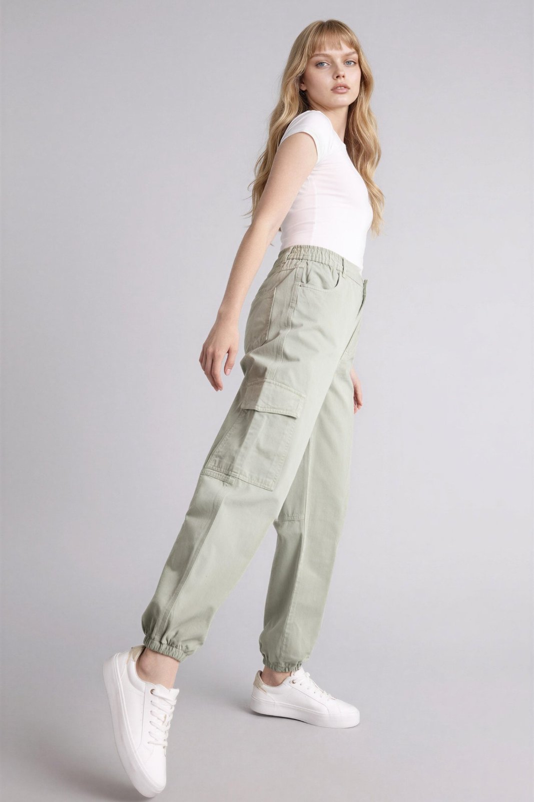  pantalon cargo vert claire présente une taille élastique à cordon de serrage et des poches à rabat caractéristiques sur les côtés.    