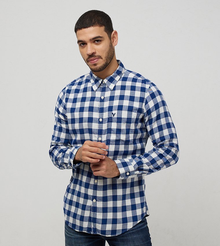 Chemise est une chemise boutonnée à manches longues à carreaux bleus et blancs de la marque American Eagle.