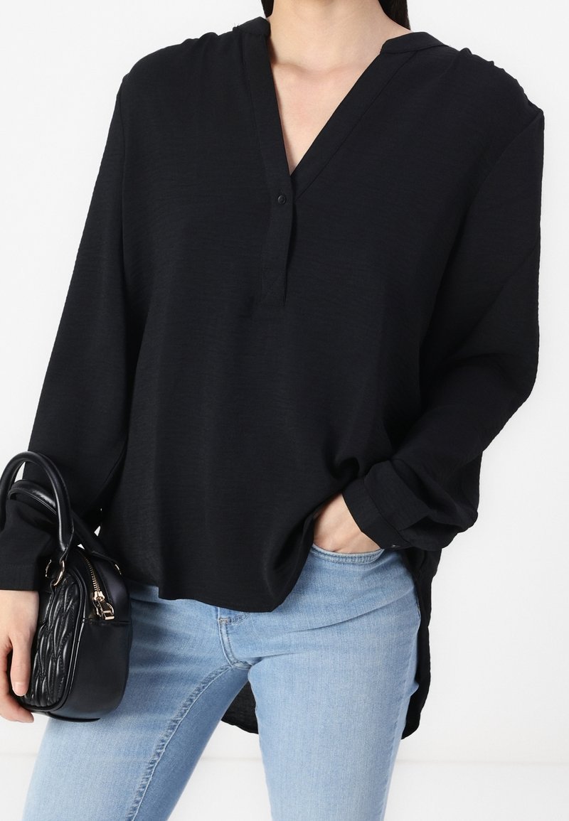 Chemisier noir est une blouse en tissu léger avec un col en V et des détails boutonnés.