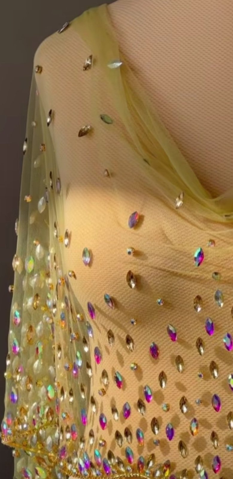 Un ensemble de vêtements composé d'un haut jaune asymétrique orné de paillettes et de perles, suspendu au-dessus d'une pantalon noire large 
