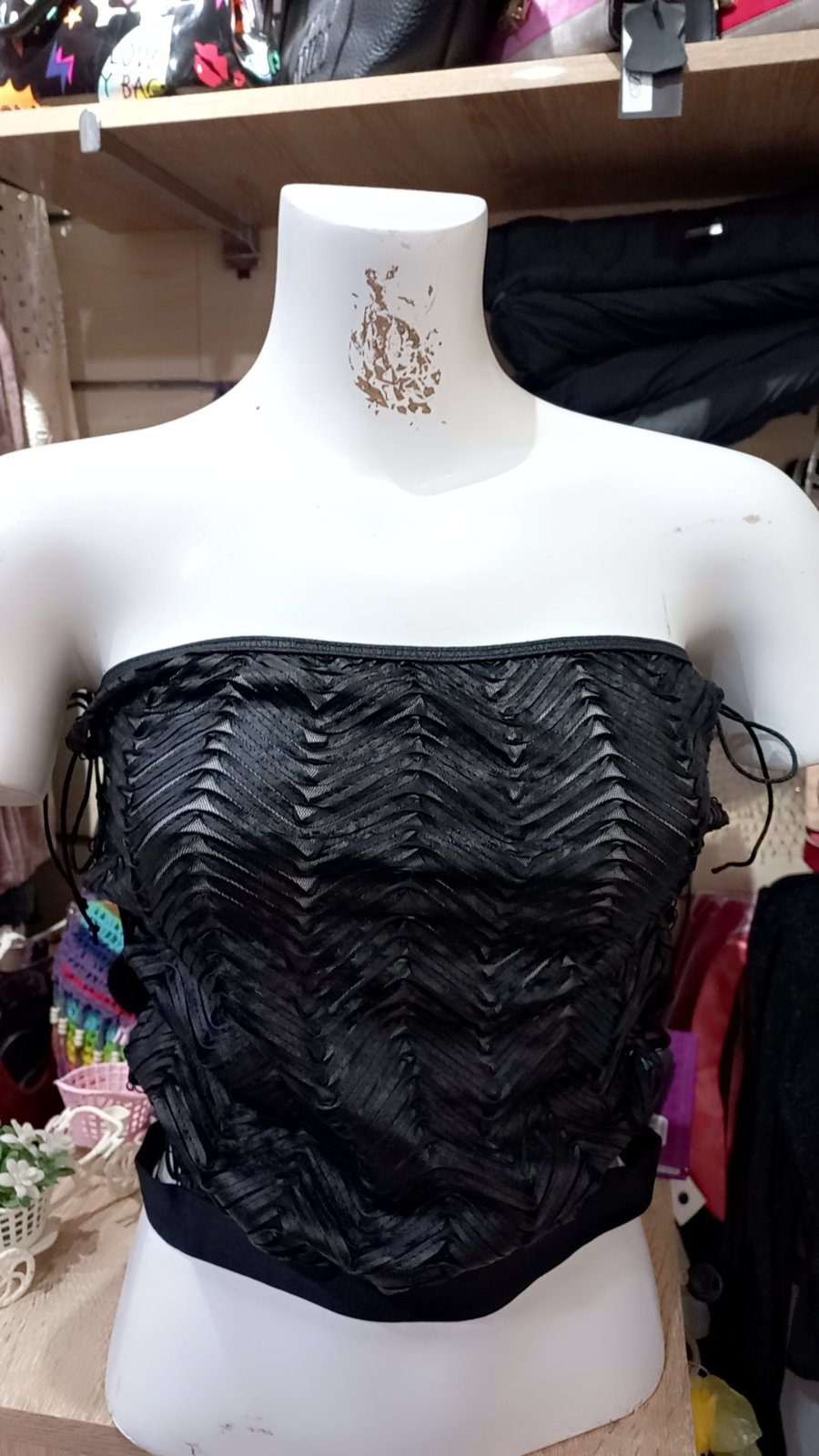 Un haut bustier noir texturé avec un motif à chevrons et des détails de laçage sur les côtés.