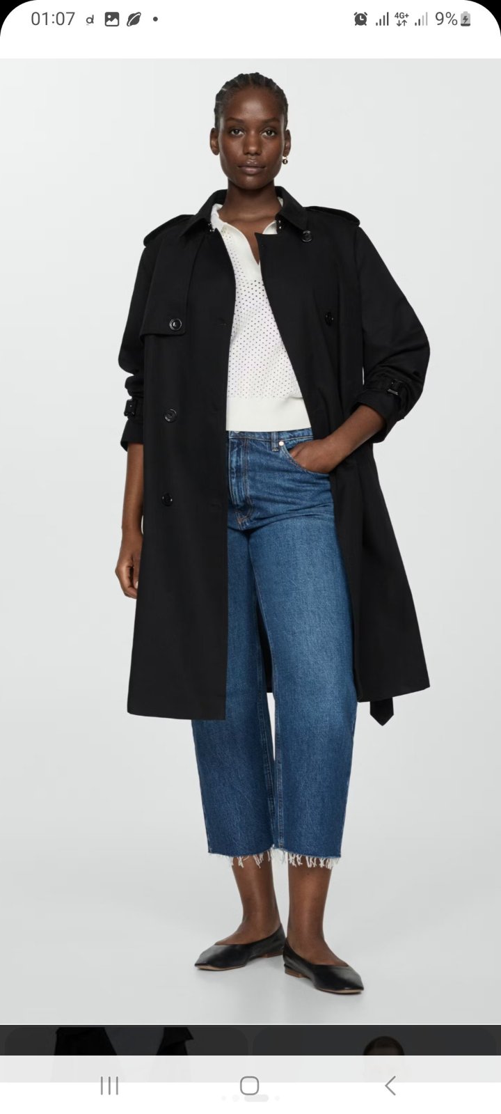 Un trench-coat noir classique à boutonnage simple, caractérisé par des détails fonctionnels tels que des pattes d'épaules et des manches avec pattes de serrage. 