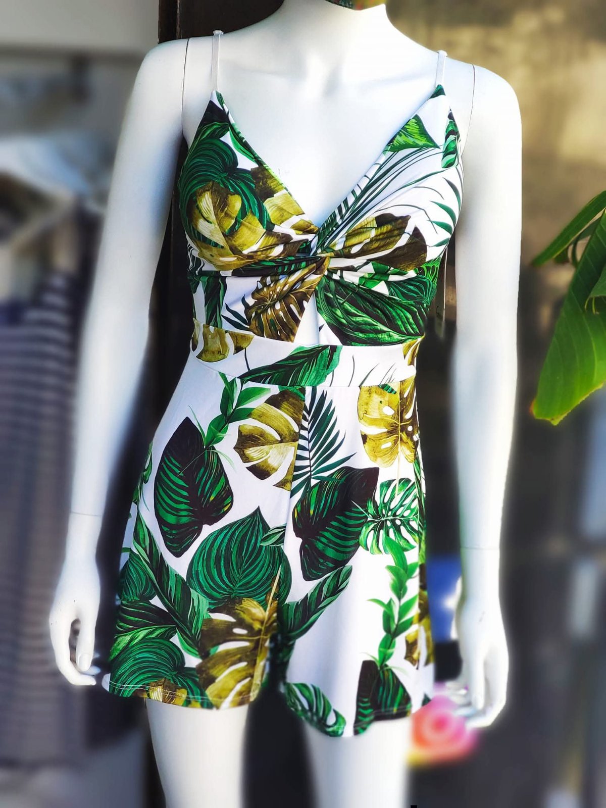 Ini-robe à bretelles fines présente un motif tropical vert et marron avec un détail nœud sur le buste.