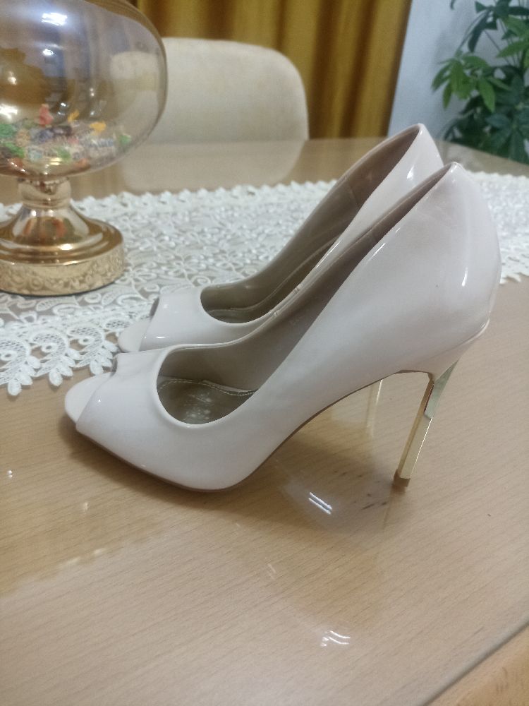 Un escarpin à bout ouvert avec finition en vernis et couleur nude 