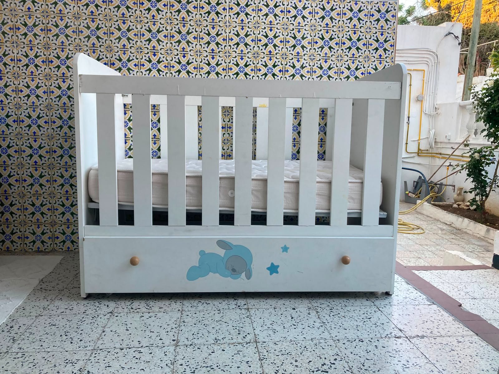 Un lit bébé avec un tiroir en dessous et un matelas  