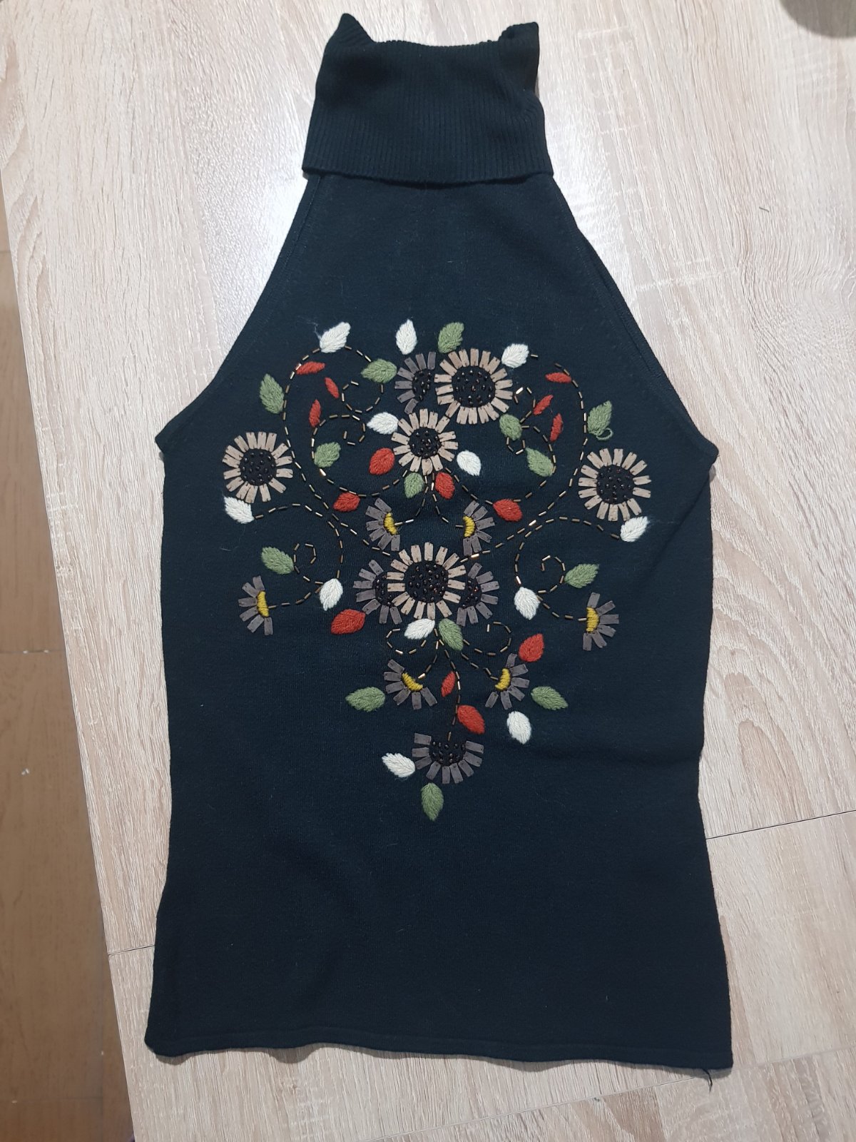 Débardeur noir de la marque bloom  à col roulé avec une broderie florale multicolore sur le devant.