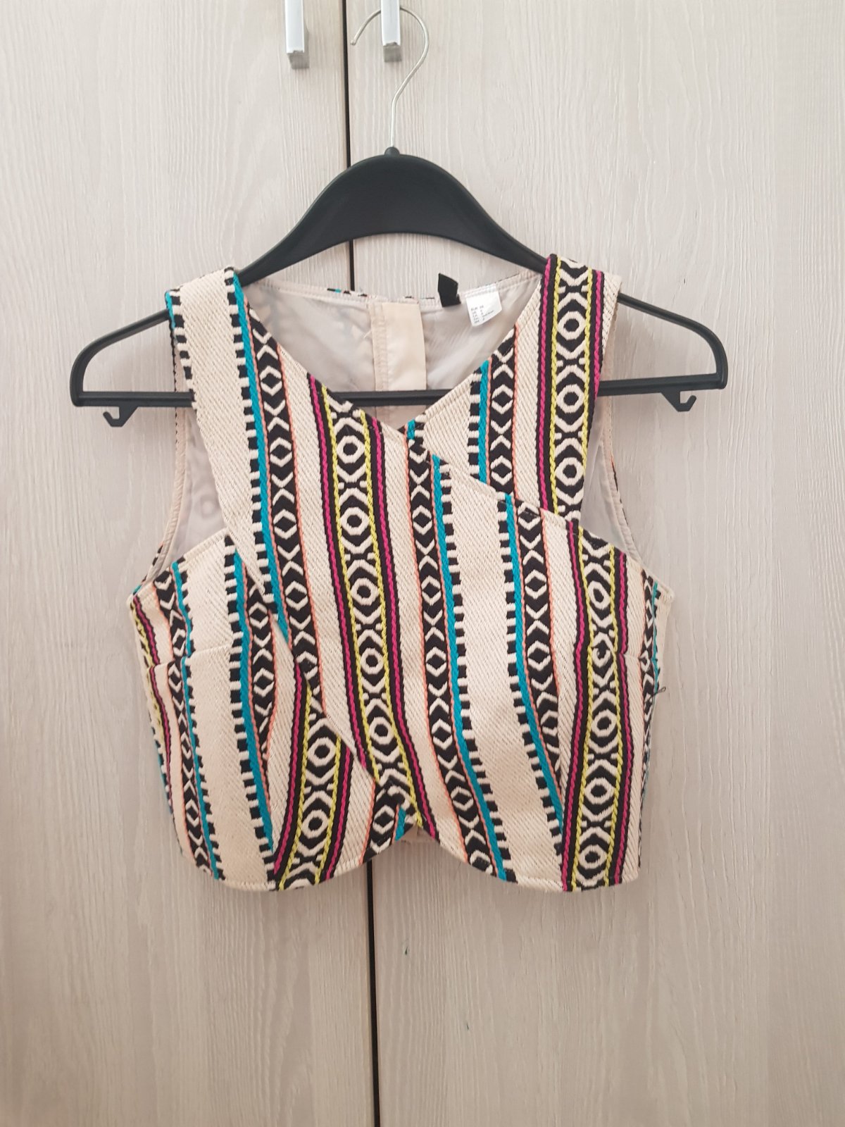Haut court à  imprimé géométrique et ethnique aux tons beige et multicolores avec un design croisé.