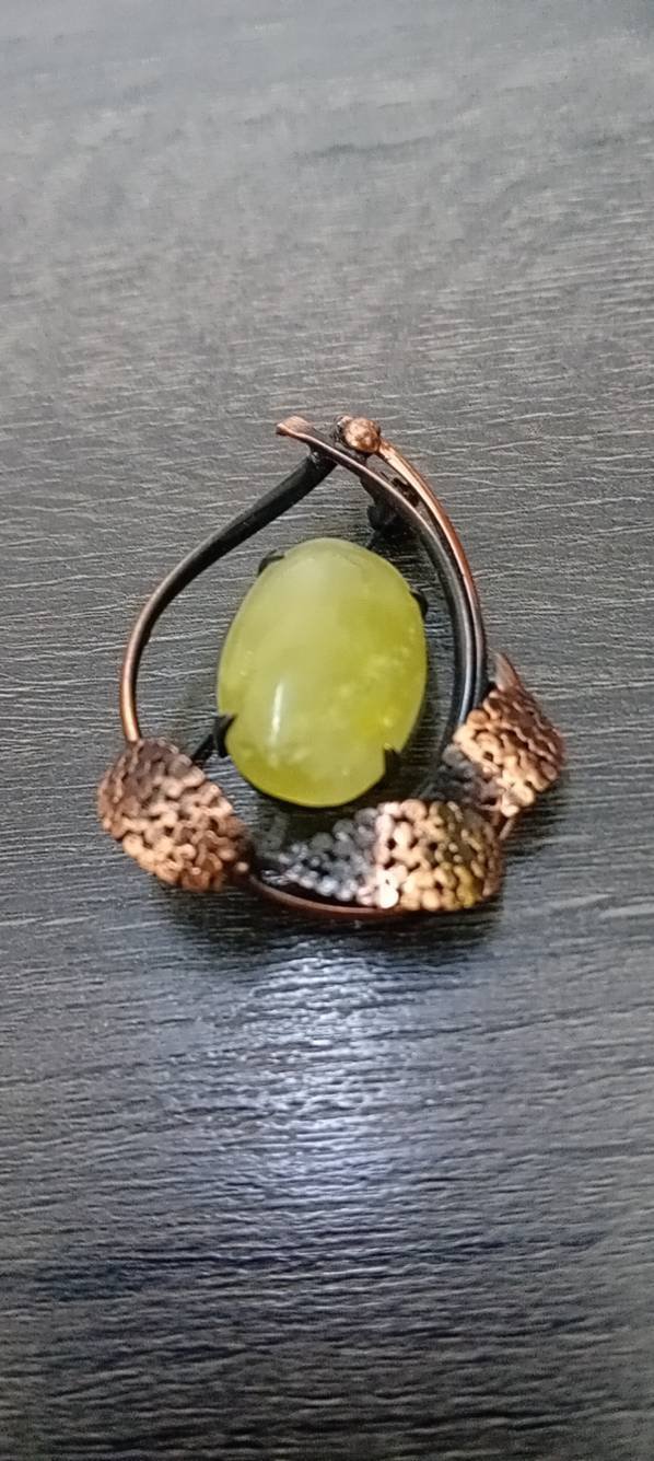 Broche artisanal portant un cabochon en serpentine verte rappelant la couleur de jade