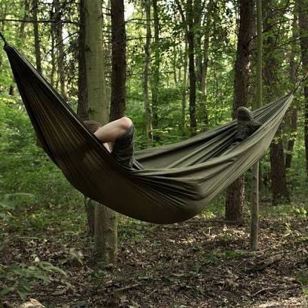 Hamac de camping ou de voyage en filet de nylon de couleur vert foncé, avec des cordes de suspension blanches.