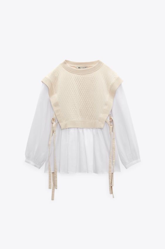 Un pull cropped beige sur une chemise blanche a manches langues 