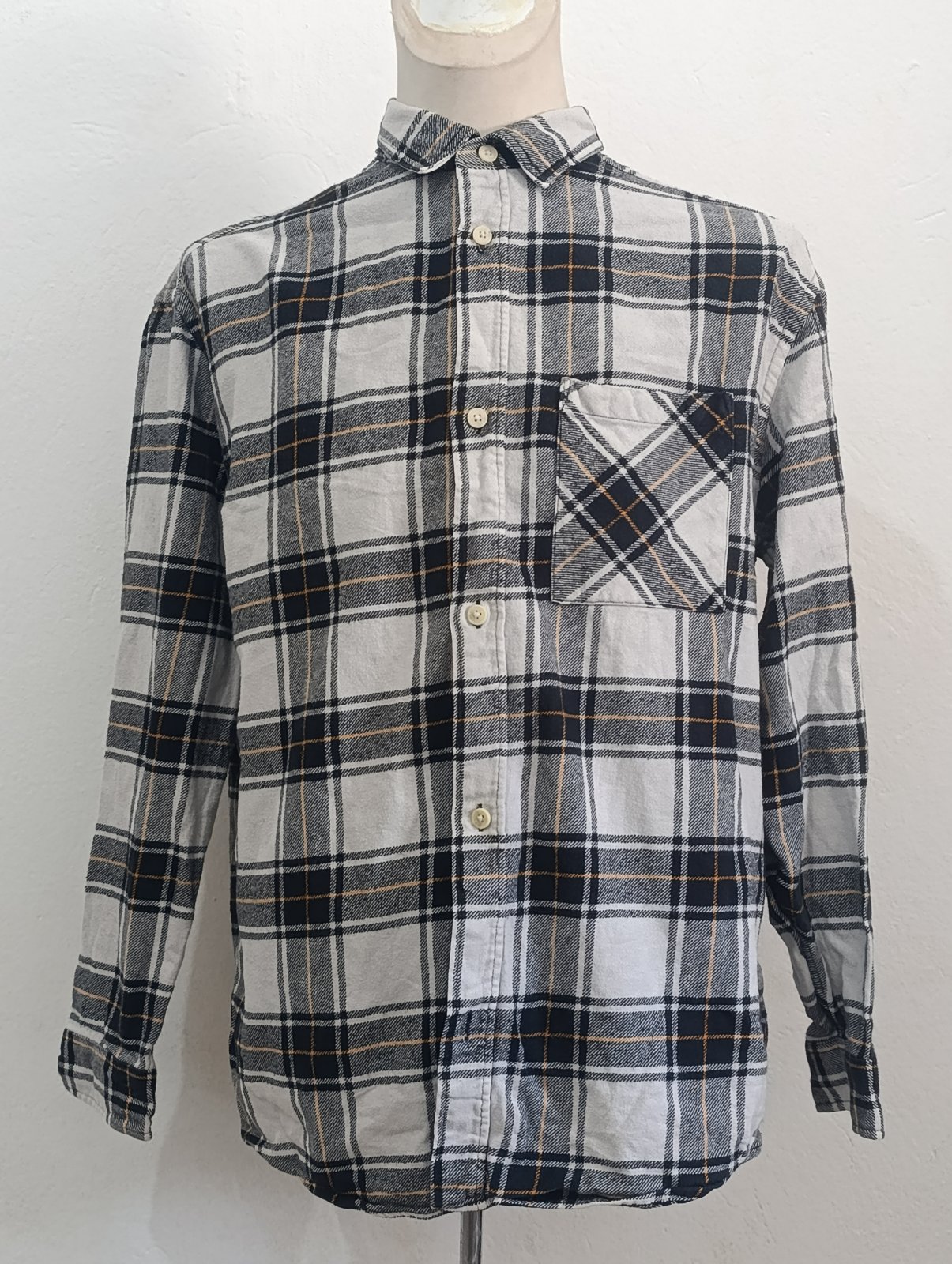 C'est une chemise en flanelle à carreaux H&M dans des tons de noir, gris et orange. 