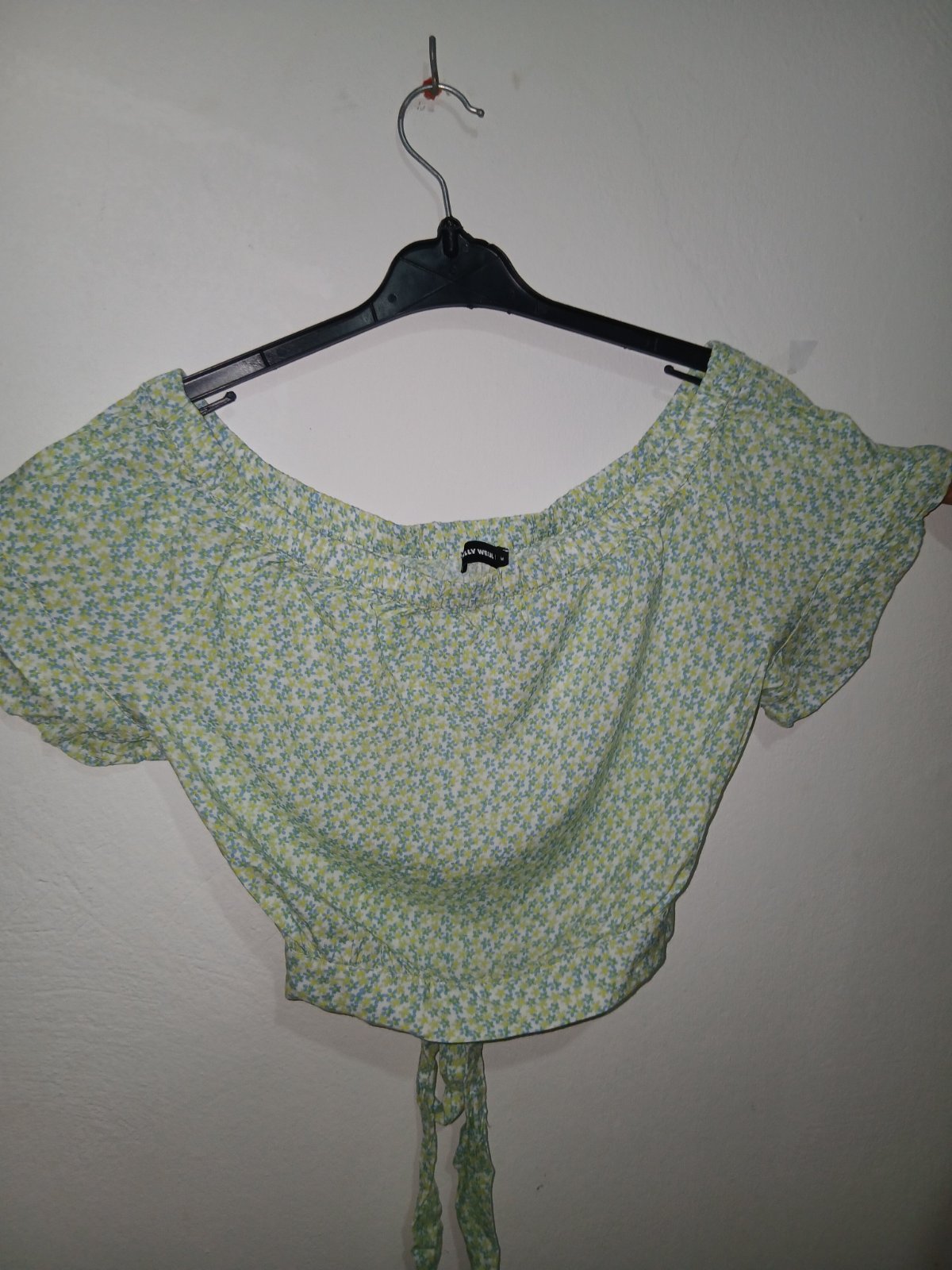 T shirt courte verte et jaune à motifs floraux est un modèle smocké à manches bouffantes.